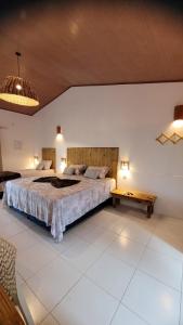 a bedroom with a large bed and a table at Vila Capininga Ecopousada in Santo Amaro