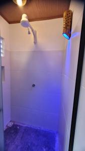 uma casa de banho com chuveiro e luz azul em Vila Capininga Ecopousada em Santo Amaro