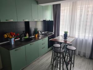 a kitchen with green cabinets and a table with stools at Mall Q4 Apartments in Bacău +14 photos