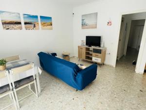 uma sala de estar com um sofá azul e uma televisão em Conil Playa, céntrico, descanso perfecto, Aire Ac y WIFI -SOLO FAMILIAS Y PAREJAS- em Conil de la Frontera
