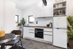 a kitchen with white cabinets and a table at Apartment 2 - Haddin Court - Stunning Executive in Blenheim