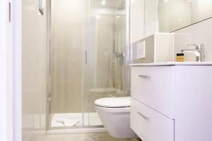 a white bathroom with a shower and a toilet at Charming Flat at Monaco's Edge in Beausoleil +4 photos