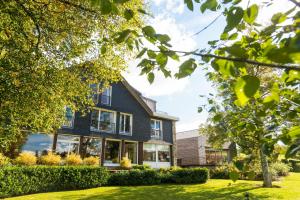 a house with large windows and a yard at Hotel des Bains & Wellness Spa Nuxe in Robertville