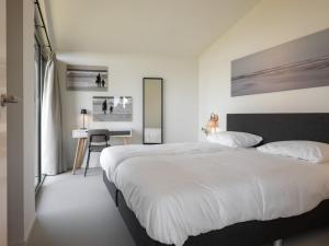 WissenkerkeにあるCottage in Wissenkerke near Het Bokkegatの大きな白いベッドと机のある寝室