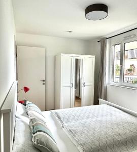ein weißes Schlafzimmer mit einem Bett und einem Fenster in der Unterkunft Vienna Sunny Side Up Apartments in Wien