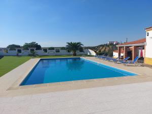 a large swimming pool with chairs and a house at Monte Santiago in Fronteira