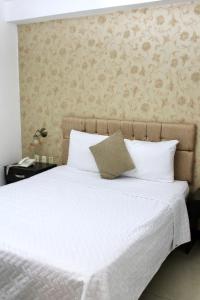 a bedroom with a large white bed with a wall at Hotel Presidente Internacional in Guayaquil