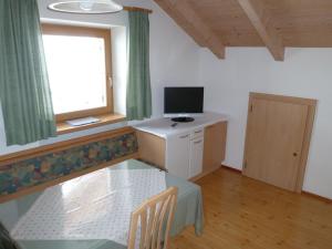 a room with a table and a television and a window at Oberpapping in San Candido