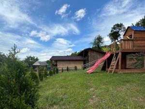 a playground with a slide and a tree house at Casuțele de sub deal in Vişeu de Sus