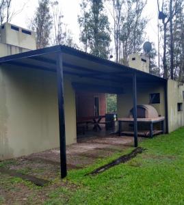 a building with a blue canopy in the grass at Campo Timbo casa con pileta in Rosario