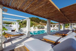 eine Terrasse mit Liegestühlen und einem Pool in der Unterkunft Ampelia Hotel Kassandra in Chaniotis