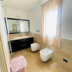 a bathroom with a sink and a toilet and a mirror at Fema House Solità in Budoni