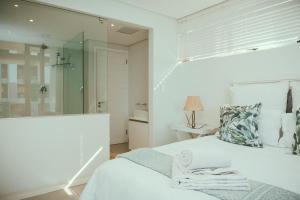 a white bedroom with a bed and a mirror at Fez@143Oceandune in Umhlanga +21 photos