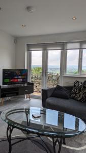 a living room with a couch and a glass table at Lane End Cottage Holmfirth - Panoramic Views, Modernised with offroad parking in Holmfirth