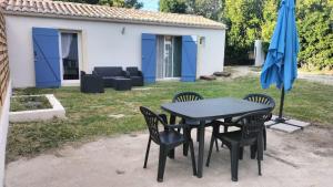 a black table and chairs with a blue umbrella at Maison de vacances en campagne in Cavaillon