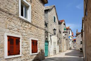 an alley with stone buildings and red shutters at Apartment Marin in Split