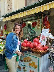 a woman standing in front of a fruit stand at Ca' Teresa in Santa Maria