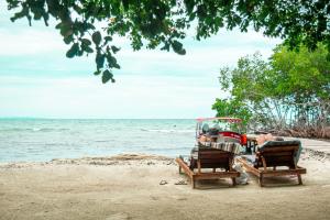twee mensen zitten in stoelen op een strand bij Secreto Hostel in Isla Grande