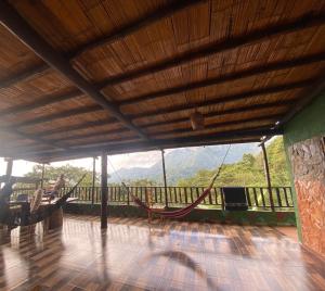 a room with a hammock on a balcony with mountains at Hostal El Santuario in Minca