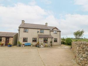 a large brick house with a stone wall at Tyn Rallt in Bodorgan