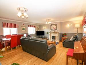 a living room with leather furniture and a fireplace at Tyn Rallt in Bodorgan