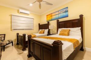 a bedroom with two beds and a ceiling fan at serendipity on the beach Ocho Rios in Saint Annʼs Bay