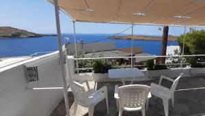 a patio with chairs and an umbrella and the ocean at Thalassino Ageri in Gialiskari
