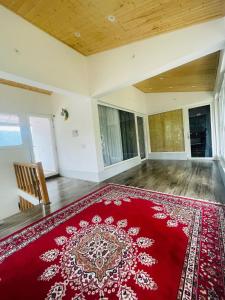 een lege kamer met een rood tapijt op de vloer bij Maan Cottages in Rāmgarh