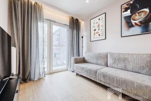 a living room with a couch and a large window at Diasfera Prestige by LookAp in Łódź