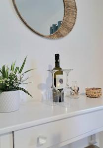 Un espejo sobre una cómoda blanca con una botella de vino. en Orion Studios B, en Centro histórico de Alónnisos