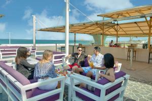 een groep mensen die rond een tafel op het strand zitten bij Radisson Blu Resort, Fujairah in Dibba