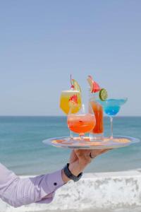 迪巴的住宿－富查伊拉雷迪森布魯酒店，持有海滩上饮料托盘的人