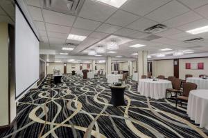 Best Western Premier Denham Inn & Suites في ليدوك: قاعة اجتماعات مع طاولات وكراسي بيضاء