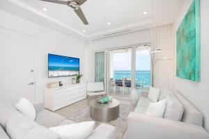 una sala de estar con muebles blancos y vistas al océano. en Rum Point Resort 308, en Driftwood Village