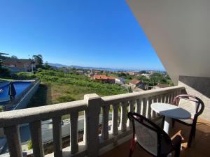 balkon z krzesłami i stołem oraz widokiem w obiekcie Duplex en Sanxenxo con piscina y vistas al mar w mieście Sanxenxo