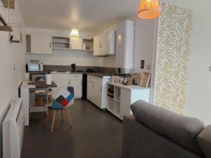 a kitchen with white cabinets and a couch and a table at Gîte PEGASUS - 5 min plage in Amfréville