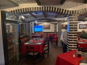 un restaurante con mesas rojas y un hombre parado frente a una TV en Hotel brisas del mar 2022 en Catia La Mar