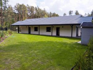 a white house with a large grass yard at Apartamenty Leśny Szum in Susiec