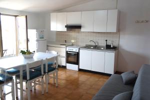 a kitchen with white cabinets and a table and a couch at MAREMEU TROPEA in Santa Domenica