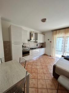 una cocina con armarios blancos y una mesa en una habitación en La casetta, en Porto SantʼElpidio