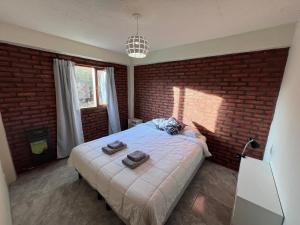 a bedroom with a large bed with a brick wall at Departamentos Centro El Calafate in El Calafate