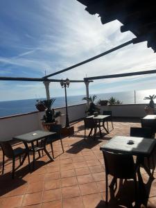 un patio con tavoli, sedie e vista sull'oceano di Hotel Punto Azzurro a Ischia