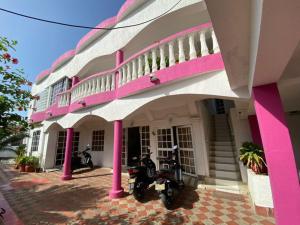 a pink and white building with motorcycles parked outside at apartaestudio sarie bay san andres islas in San Andrés