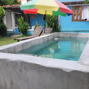 una piscina con sombrilla junto a una casa en Casa Beija-flor, en Isla de Boipeba