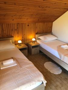 a room with two beds and two tables with lamps at Apartments Ruza in Ražanj