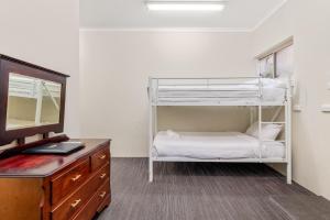 Zimmer mit einem Etagenbett, einem Schreibtisch und einem TV in der Unterkunft Sanctuary Resort Motor Inn in Coffs Harbour