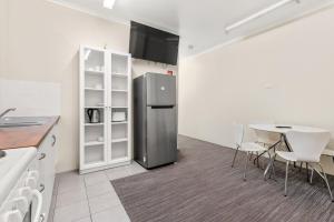eine Küche mit einem Kühlschrank aus Edelstahl und einem Tisch in der Unterkunft Sanctuary Resort Motor Inn in Coffs Harbour