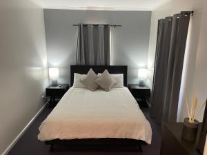um quarto com uma cama branca com duas mesas de cabeceira em Alpine Village Jindabyne em Jindabyne