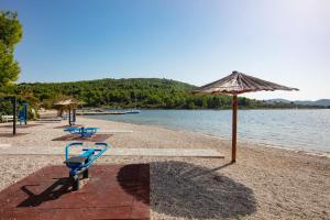 a beach with two blue benches and an umbrella at Family friendly house with a swimming pool Dazlina, Sibenik - 23303 in Tisno