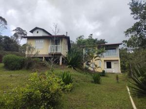 a yellow house on a hill with a yard at Chalés Lavras de Minas - Amar in Lavras Novas